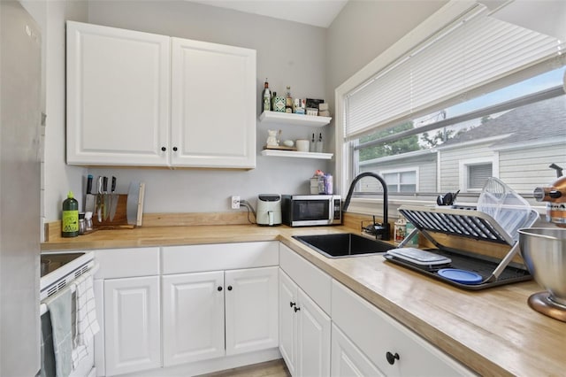 1525 38th Ave N, Saint Petersburg, FL 33704 - kitchen with white range with electric cooktop, a sink, white cabinets, and wood counters