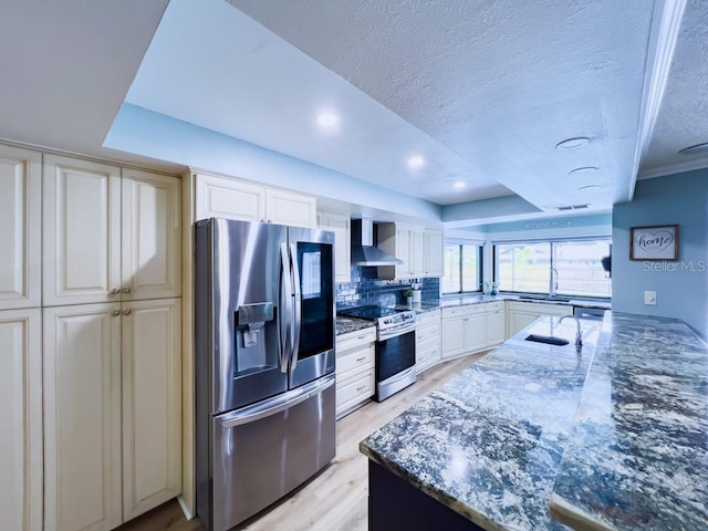 3005 Wilton Ln, Valrico, FL 33596 - kitchen featuring appliances with stainless steel finishes, wall chimney exhaust hood, a sink, light wood-type flooring, and dark stone countertops
