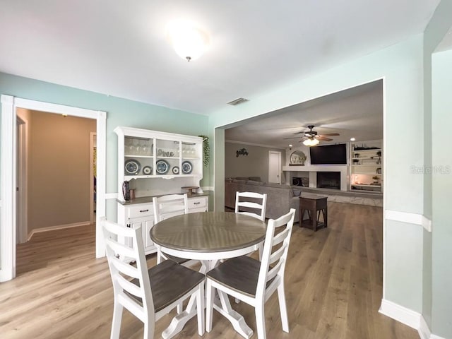 3005 Wilton Ln, Valrico, FL 33596 - dining room featuring ceiling fan, light wood finished floors, baseboards, and a fireplace with raised hearth