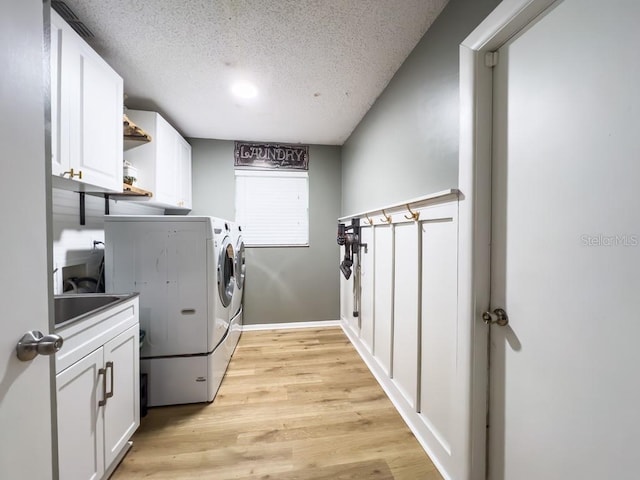 3005 Wilton Ln, Valrico, FL 33596 - laundry room featuring separate washer and dryer, cabinet space, a textured ceiling, light wood-type flooring, and baseboards