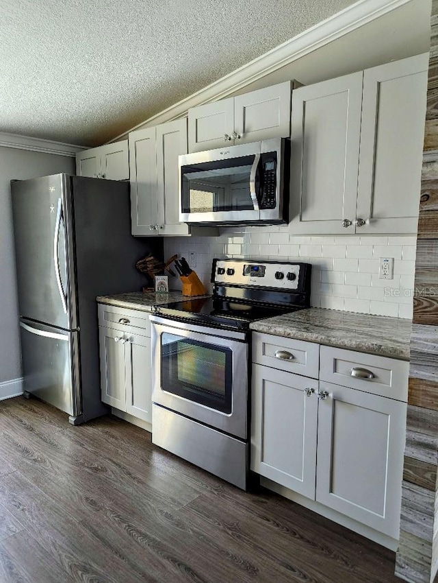 85 Heather Point Ct Unit 850, New Smyrna Beach, FL 32169 - kitchen with appliances with stainless steel finishes, a textured ceiling, ornamental molding, backsplash, and dark wood-style flooring