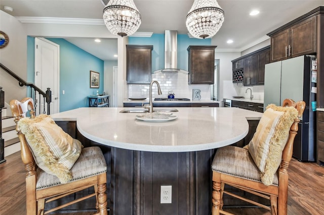 14110 Barrington Stowers Dr, Lithia, FL 33547 - kitchen featuring freestanding refrigerator, wall chimney range hood, dark brown cabinetry, a chandelier, and crown molding