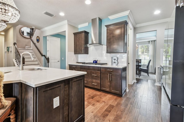 14110 Barrington Stowers Dr, Lithia, FL 33547 - kitchen with a sink, wall chimney range hood, stainless steel gas cooktop, dark brown cabinetry, and light countertops