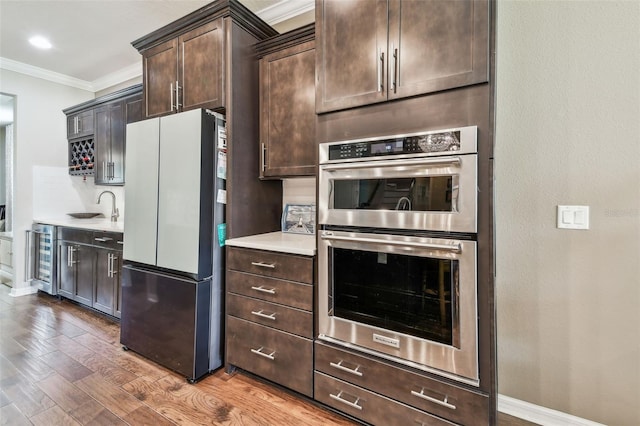 14110 Barrington Stowers Dr, Lithia, FL 33547 - kitchen with freestanding refrigerator, stainless steel double oven, ornamental molding, a sink, and dark brown cabinetry