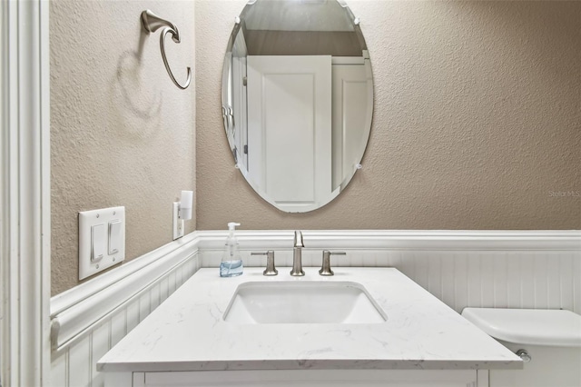 14110 Barrington Stowers Dr, Lithia, FL 33547 - bathroom featuring wainscoting, vanity, toilet, and a textured wall