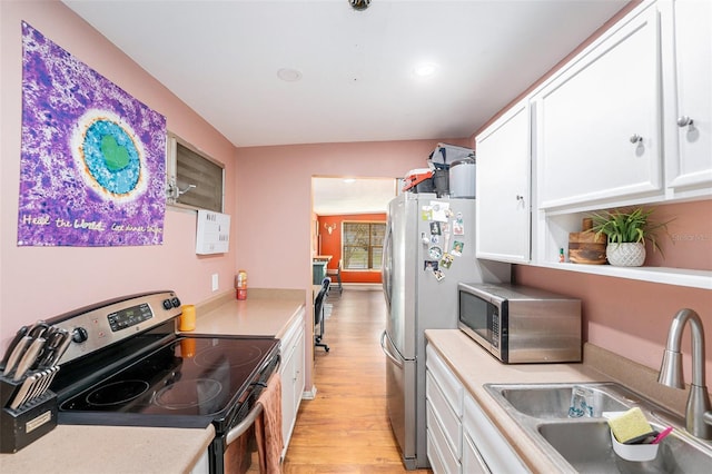 8556 91st Ter, Seminole, FL 33777 - kitchen with appliances with stainless steel finishes, a sink, light wood-style floors, white cabinets, and light countertops