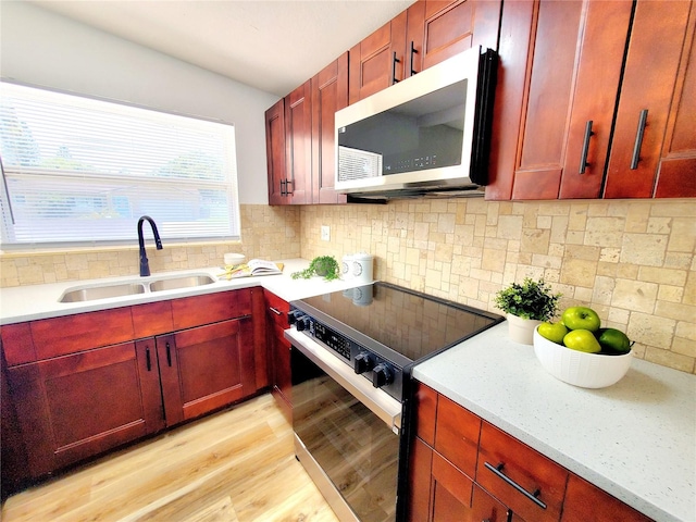 1373 Fairfax Rd, Clearwater, FL 33764 - kitchen featuring electric range, stainless steel microwave, reddish brown cabinets, and light wood-style flooring