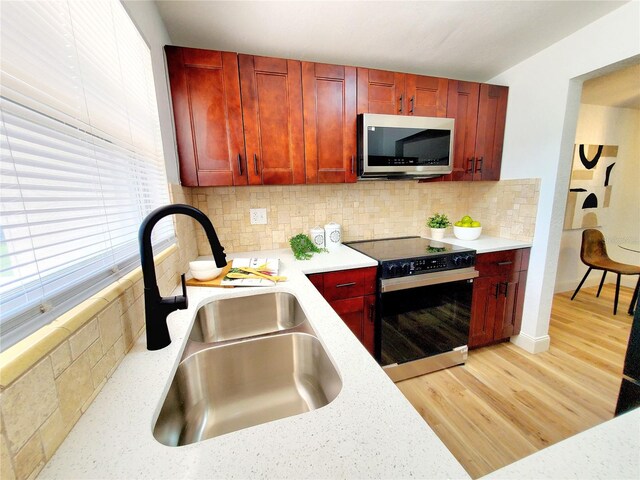 1373 Fairfax Rd, Clearwater, FL 33764 - kitchen with stainless steel microwave, range with electric stovetop, reddish brown cabinets, and light wood-style floors