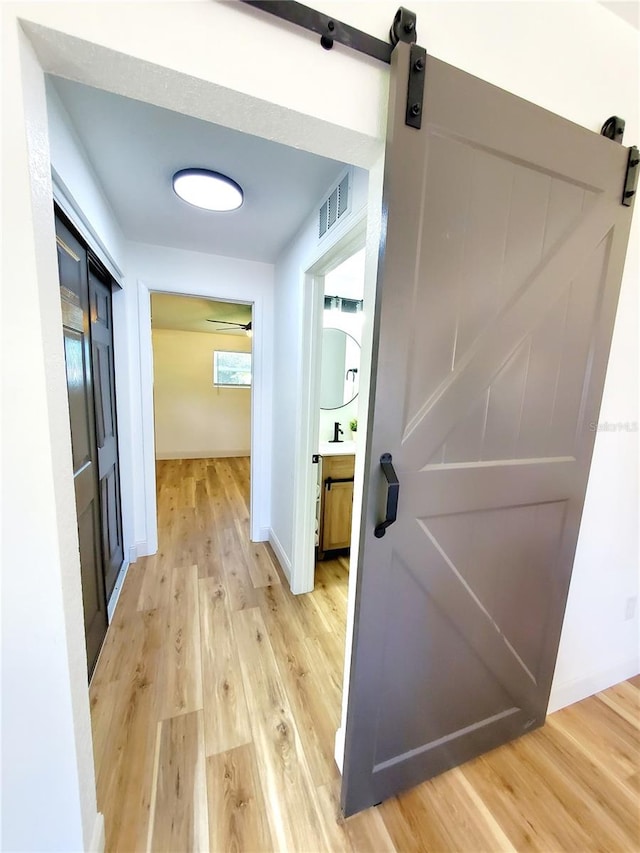 1373 Fairfax Rd, Clearwater, FL 33764 - corridor with a barn door and light wood-style flooring