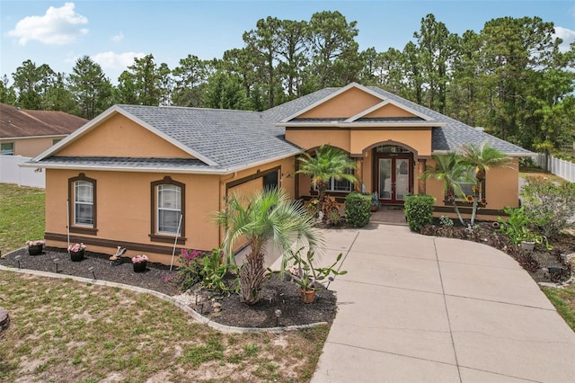 14494 Copeland Way, Brooksville, FL 34604 - view of front of house featuring stucco siding, a garage, driveway, french doors, and roof with shingles