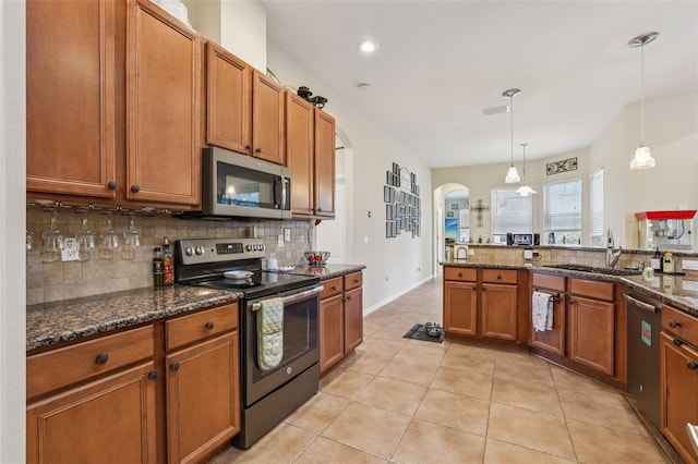 14494 Copeland Way, Brooksville, FL 34604 - kitchen with stainless steel appliances, a sink, tasteful backsplash, arched walkways, and brown cabinetry