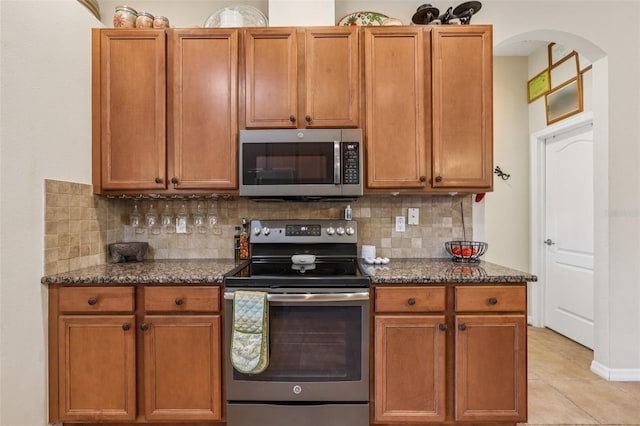 14494 Copeland Way, Brooksville, FL 34604 - kitchen with appliances with stainless steel finishes, decorative backsplash, dark stone countertops, and light tile patterned flooring