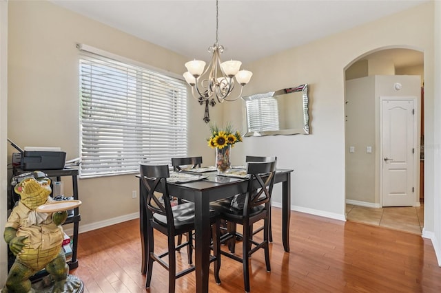 14494 Copeland Way, Brooksville, FL 34604 - dining space with arched walkways, a chandelier, hardwood / wood-style floors, and baseboards