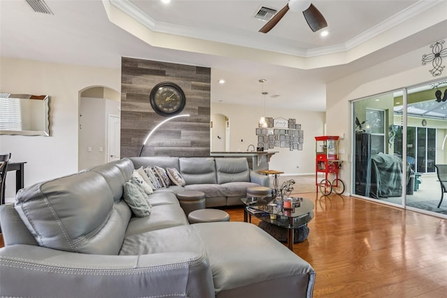 14494 Copeland Way, Brooksville, FL 34604 - living room featuring arched walkways, a raised ceiling, a ceiling fan, wood finished floors, and ornamental molding
