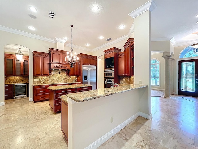 27511 Hialeah Way, Wesley Chapel, FL 33544 - kitchen with stainless steel appliances, ornate columns, arched walkways, beverage cooler, and decorative backsplash
