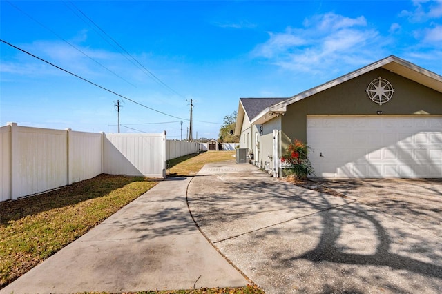 6143 Black Walnut Dr, Bartow, FL 33830 - view of side of home with concrete driveway, stucco siding, an attached garage, and central AC unit