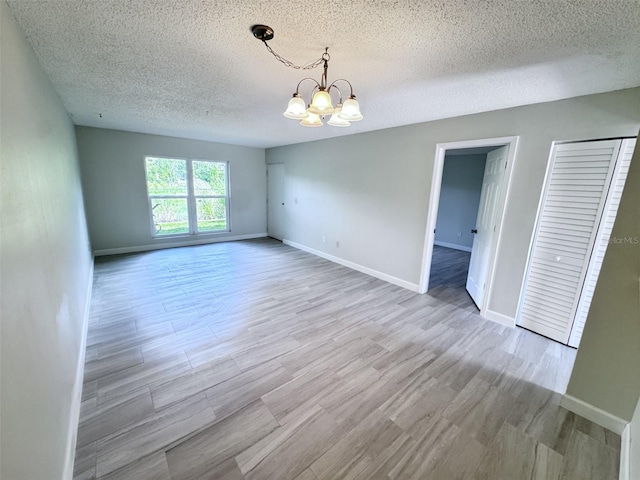 2625 State Road 590 Unit 1012, Clearwater, FL 33759 - spare room with a chandelier, a textured ceiling, baseboards, and wood finished floors