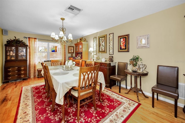 1151 Lancer Ln, Tarpon Springs, FL 34689 - dining room with a chandelier, light wood-style flooring, and baseboards