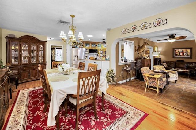 1151 Lancer Ln, Tarpon Springs, FL 34689 - dining space with arched walkways, a chandelier, wood finished floors, and a ceiling fan