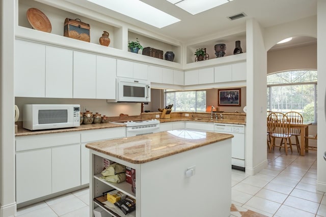 3452 Forelock Rd, Tarpon Springs, FL 34688 - kitchen featuring white appliances, open shelves, light tile patterned floors, a kitchen island, and arched walkways