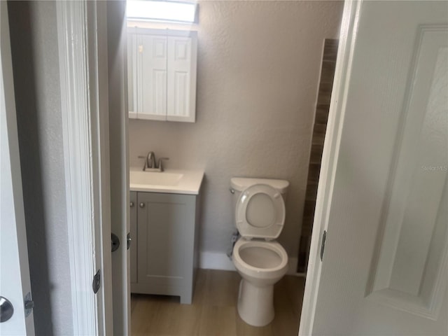 8502 Grapefruit Ave, Tampa, FL 33619 - bathroom with vanity, toilet, wood finished floors, and a textured wall