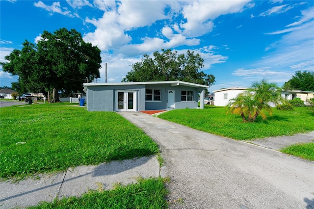 8502 Grapefruit Ave, Tampa, FL 33619 - mid-century home with french doors, a front lawn, driveway, and stucco siding