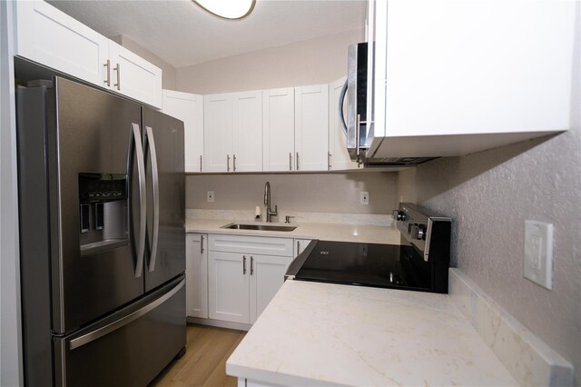 8502 Grapefruit Ave, Tampa, FL 33619 - kitchen featuring appliances with stainless steel finishes, light countertops, white cabinetry, and light wood finished floors