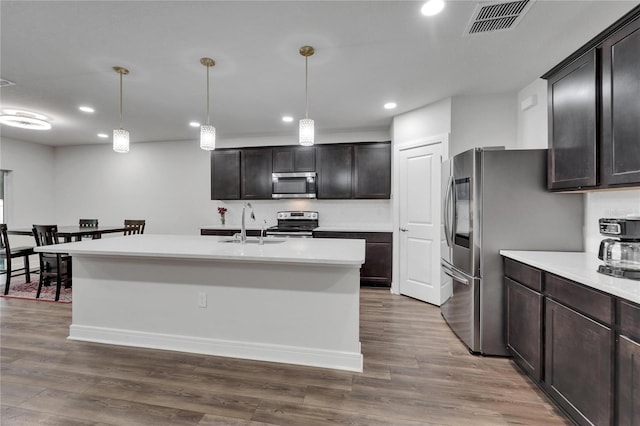 6658 Devlin Ln, Wesley Chapel, FL 33545 - kitchen with stainless steel appliances, recessed lighting, a sink, light countertops, and wood finished floors