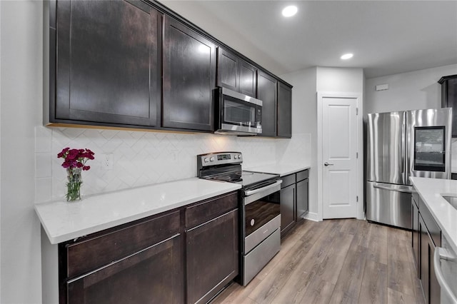 6658 Devlin Ln, Wesley Chapel, FL 33545 - kitchen with stainless steel appliances, tasteful backsplash, light countertops, light wood-style flooring, and recessed lighting