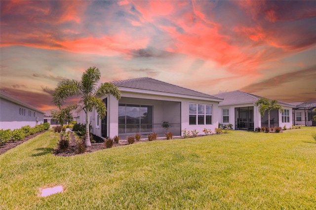 16126 San Donato Pl, Bradenton, FL 34211 - rear view of property with a tile roof, a lawn, stucco siding, and a sunroom