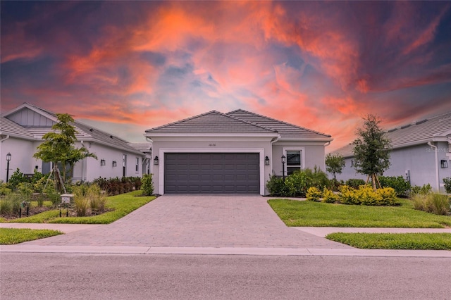 16126 San Donato Pl, Bradenton, FL 34211 - view of front facade with an attached garage, decorative driveway, a front yard, a tile roof, and stucco siding