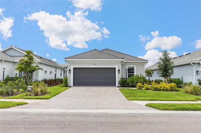16126 San Donato Pl, Bradenton, FL 34211 - ranch-style house with a garage, decorative driveway, a front yard, stucco siding, and a tiled roof