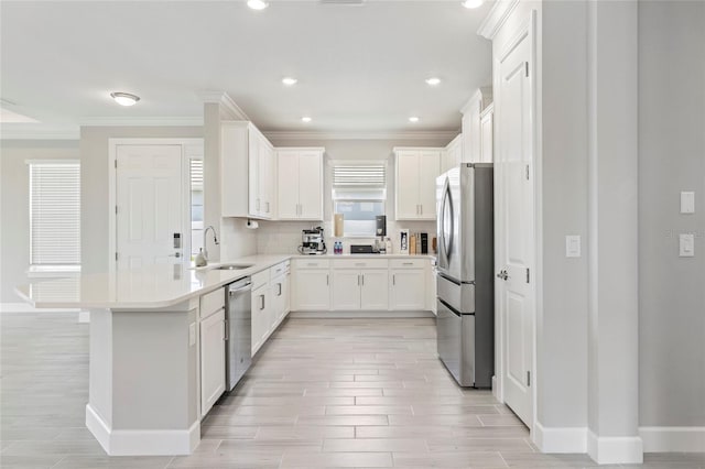 16126 San Donato Pl, Bradenton, FL 34211 - kitchen with stainless steel appliances, ornamental molding, wood tiled floors, a peninsula, and light countertops