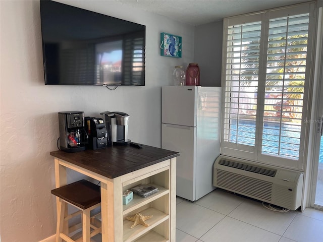 800 Bayway Blvd Unit 14, Clearwater Beach, FL 33767 - kitchen with freestanding refrigerator, light tile patterned floors, a wall mounted AC, and a textured wall