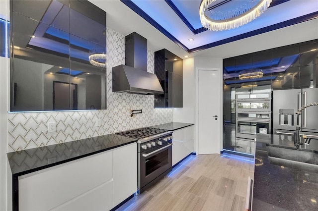 6528 Simone Shores Cir, Apollo Beach, FL 33572 - kitchen with wall chimney range hood, a raised ceiling, stainless steel appliances, modern cabinets, and backsplash