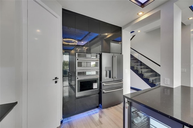 6528 Simone Shores Cir, Apollo Beach, FL 33572 - kitchen featuring appliances with stainless steel finishes, light wood-style floors, dark stone countertops, dark cabinets, and modern cabinets
