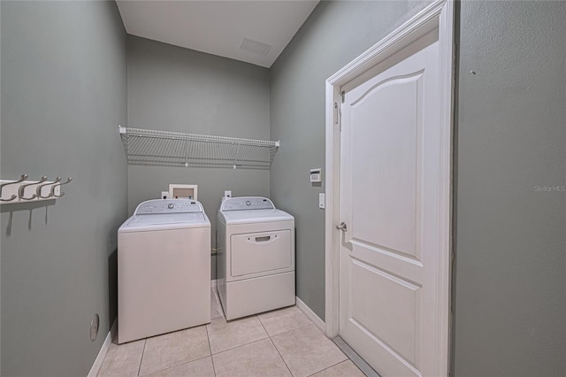 20109 Bay Cedar Ave, Tampa, FL 33647 - laundry room featuring washer and clothes dryer, light tile patterned floors, and baseboards