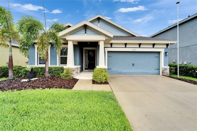 6127 Colmar Pl, Apollo Beach, FL 33572 - view of front of house featuring driveway, a garage, stone siding, a front lawn, and stucco siding