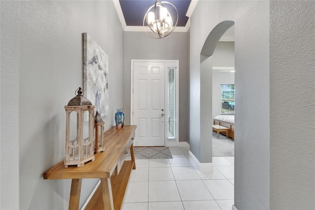 6127 Colmar Pl, Apollo Beach, FL 33572 - foyer entrance with a chandelier, arched walkways, ornamental molding, a textured wall, and light tile patterned floors