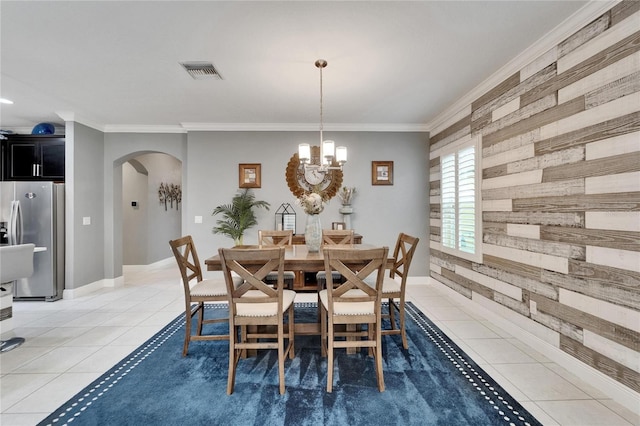 6127 Colmar Pl, Apollo Beach, FL 33572 - dining space featuring arched walkways, wooden walls, light tile patterned flooring, a chandelier, and crown molding