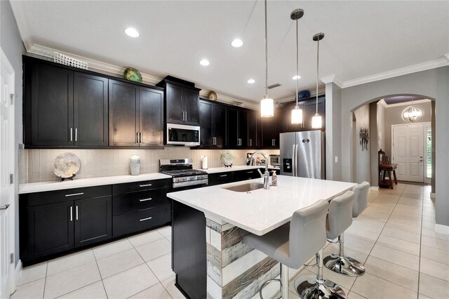 6127 Colmar Pl, Apollo Beach, FL 33572 - kitchen featuring stainless steel appliances, ornamental molding, a sink, arched walkways, and light tile patterned floors