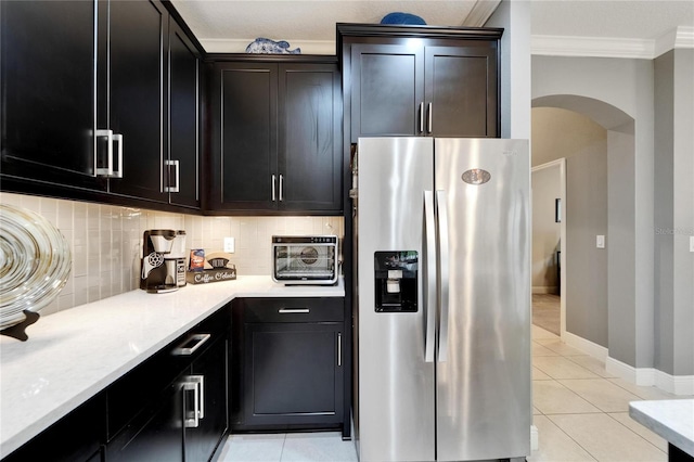 6127 Colmar Pl, Apollo Beach, FL 33572 - kitchen featuring stainless steel fridge, arched walkways, crown molding, light tile patterned floors, and decorative backsplash
