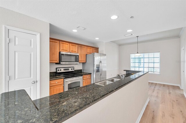 113 S Sherrill St Unit 113, Tampa, FL 33609 - kitchen with stainless steel appliances, a sink, light wood finished floors, brown cabinets, and baseboards