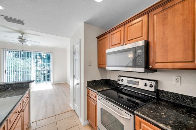 113 S Sherrill St Unit 113, Tampa, FL 33609 - kitchen featuring appliances with stainless steel finishes, a ceiling fan, brown cabinets, light tile patterned flooring, and dark stone counters