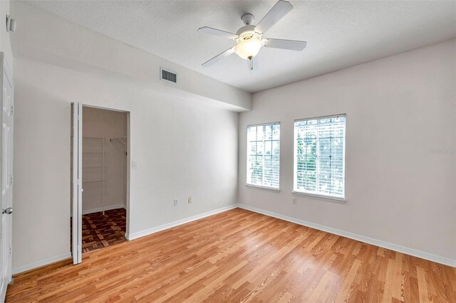 113 S Sherrill St Unit 113, Tampa, FL 33609 - empty room with light wood finished floors, a ceiling fan, baseboards, and a textured ceiling