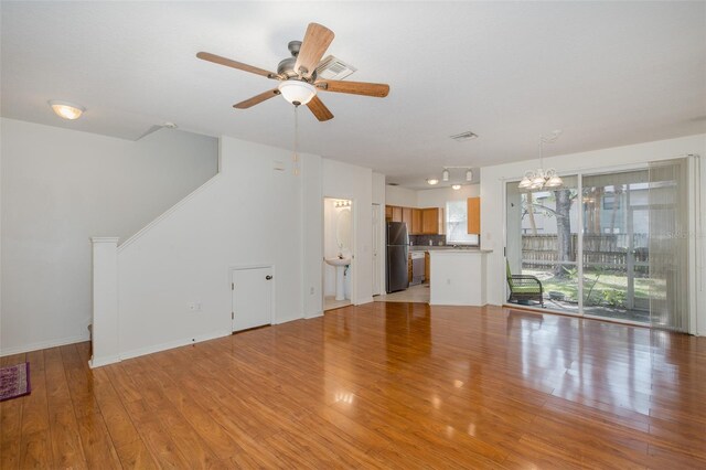 13521 Forest Lake Dr, Largo, FL 33771 - unfurnished living room with a chandelier, plenty of natural light, light wood-style floors, and a ceiling fan