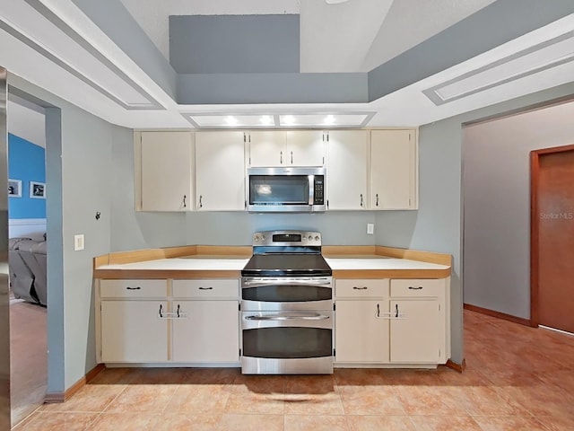 13094 Huntington Woods Ave, Spring Hill, FL 34609 - kitchen with stainless steel appliances, light countertops, cream cabinets, baseboards, and a raised ceiling