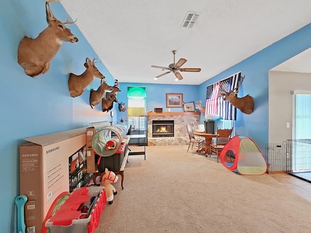 13094 Huntington Woods Ave, Spring Hill, FL 34609 - rec room featuring a stone fireplace, carpet flooring, healthy amount of natural light, a ceiling fan, and a textured ceiling