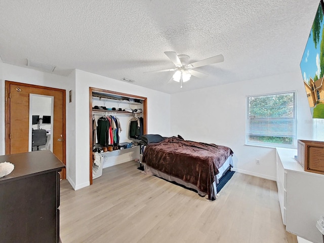 13094 Huntington Woods Ave, Spring Hill, FL 34609 - bedroom with light wood finished floors, baseboards, a textured ceiling, a closet, and a ceiling fan