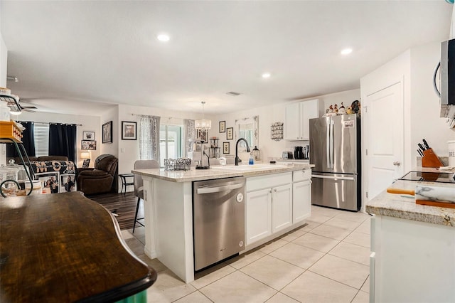 7639 Broad Pointe Dr, Zephyrhills, FL 33540 - kitchen featuring appliances with stainless steel finishes, open floor plan, white cabinets, an island with sink, and light tile patterned flooring